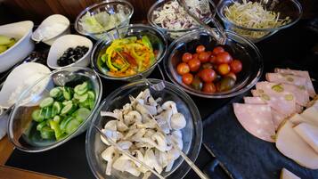 Una mesa con diversos alimentos, como rodajas de pepino, champiñones, tomates y carne cortada.