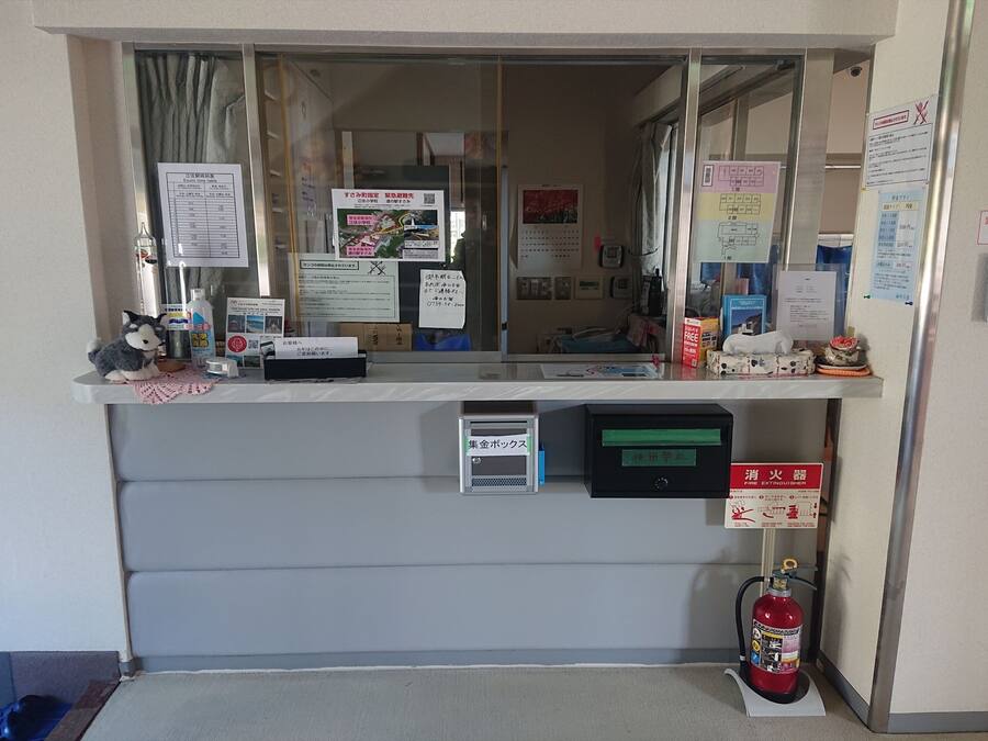 Un comptoir d’accueil avec des affiches d’information, un extincteur et une petite caisse enregistreuse.