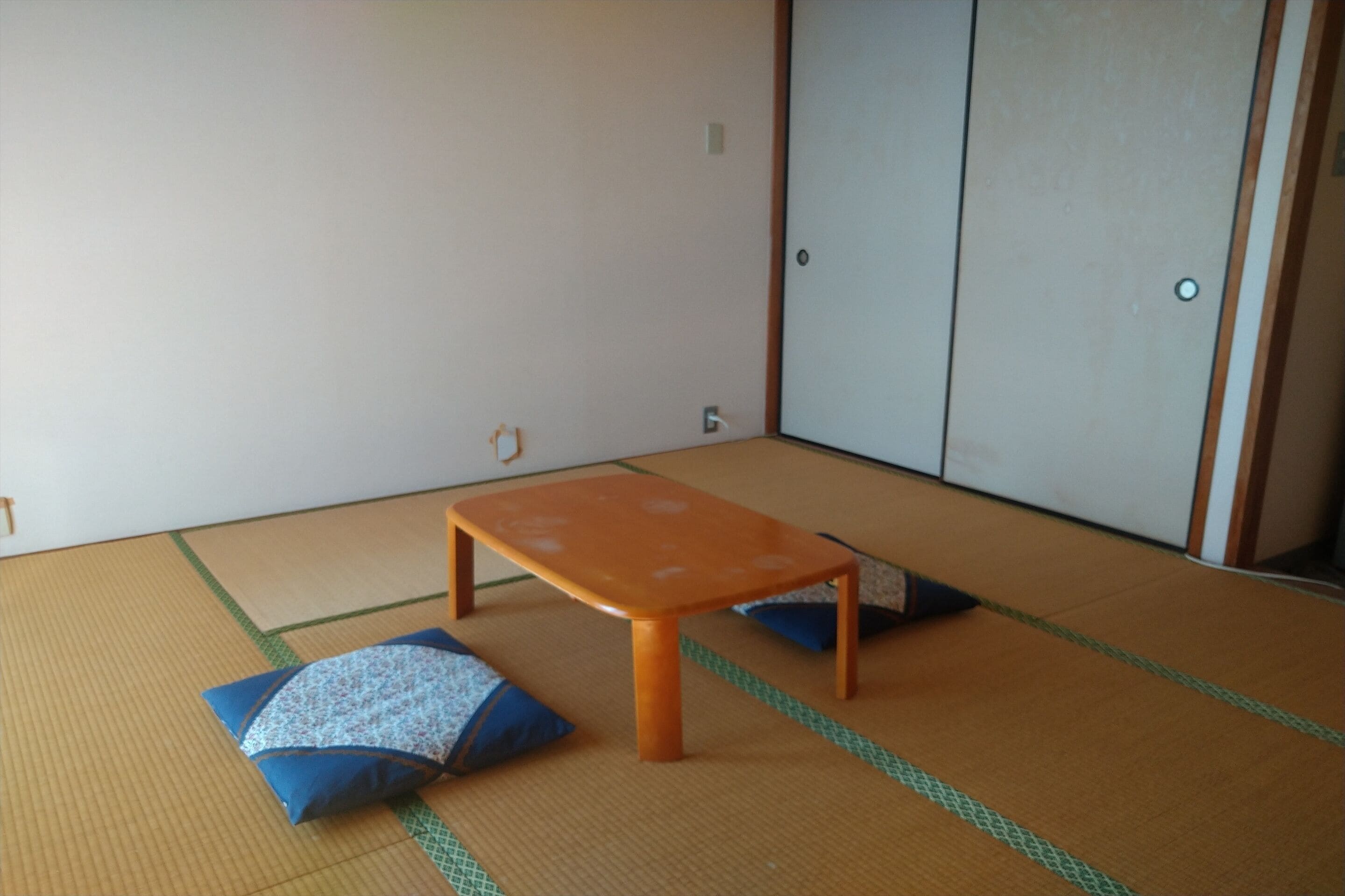 A tatami mat room with a low wooden table and cushions.