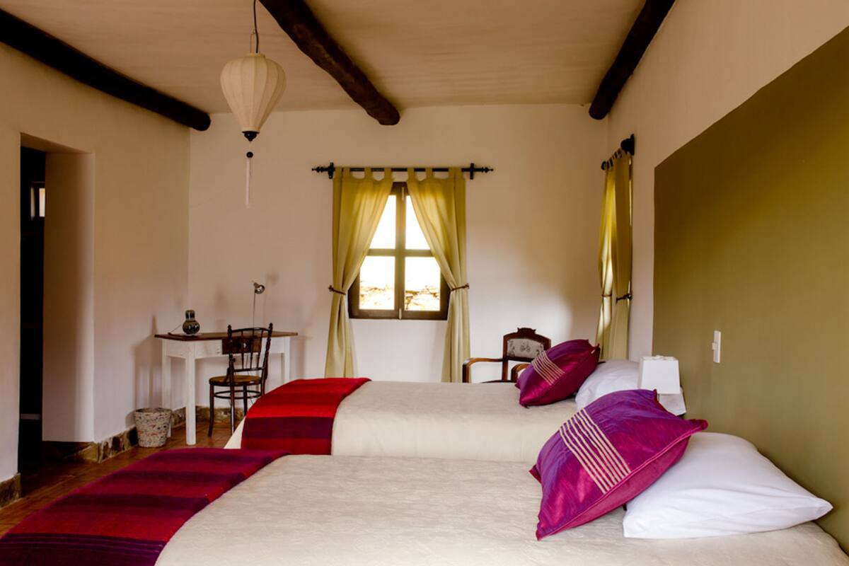 A room with two beds, a desk, and a chair.