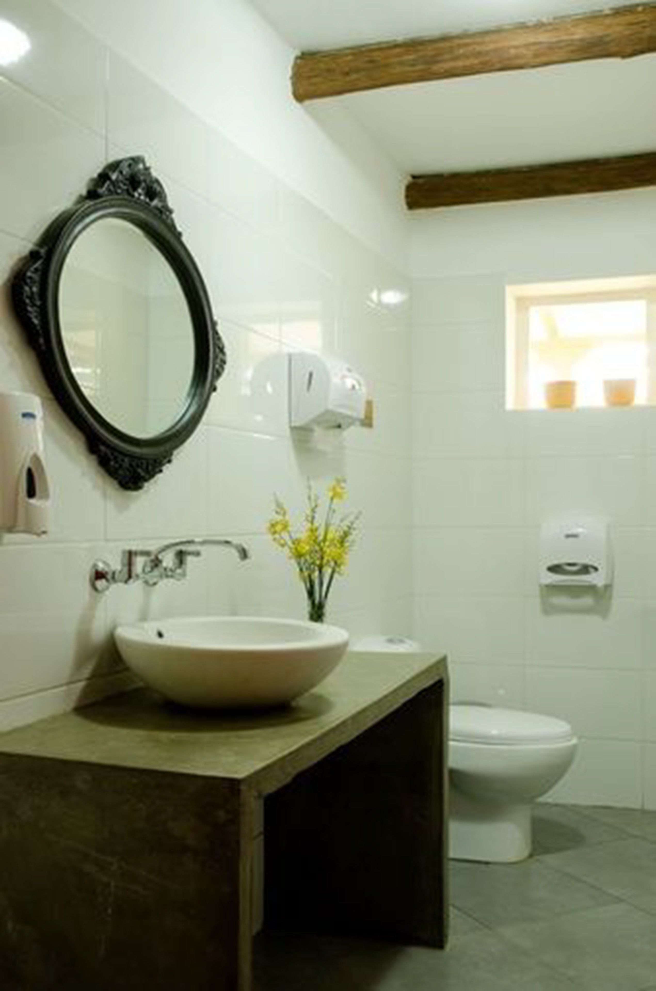 A bathroom with a white sink, a mirror, a toilet, and a window.