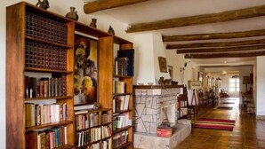 A library with wooden bookshelves, a fireplace, and a stone wall. - Tambo Sapalanchan Lodge (Lámud)
