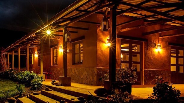 A building with a covered porch, multiple windows, and outdoor lighting. - Tambo Sapalanchan Lodge (Lámud)