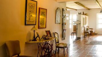 A spacious hallway with a tiled floor, a wooden chair, a table with a lamp, and framed artwork on the wall.
