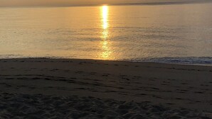 Una playa con un atardecer sobre el agua.