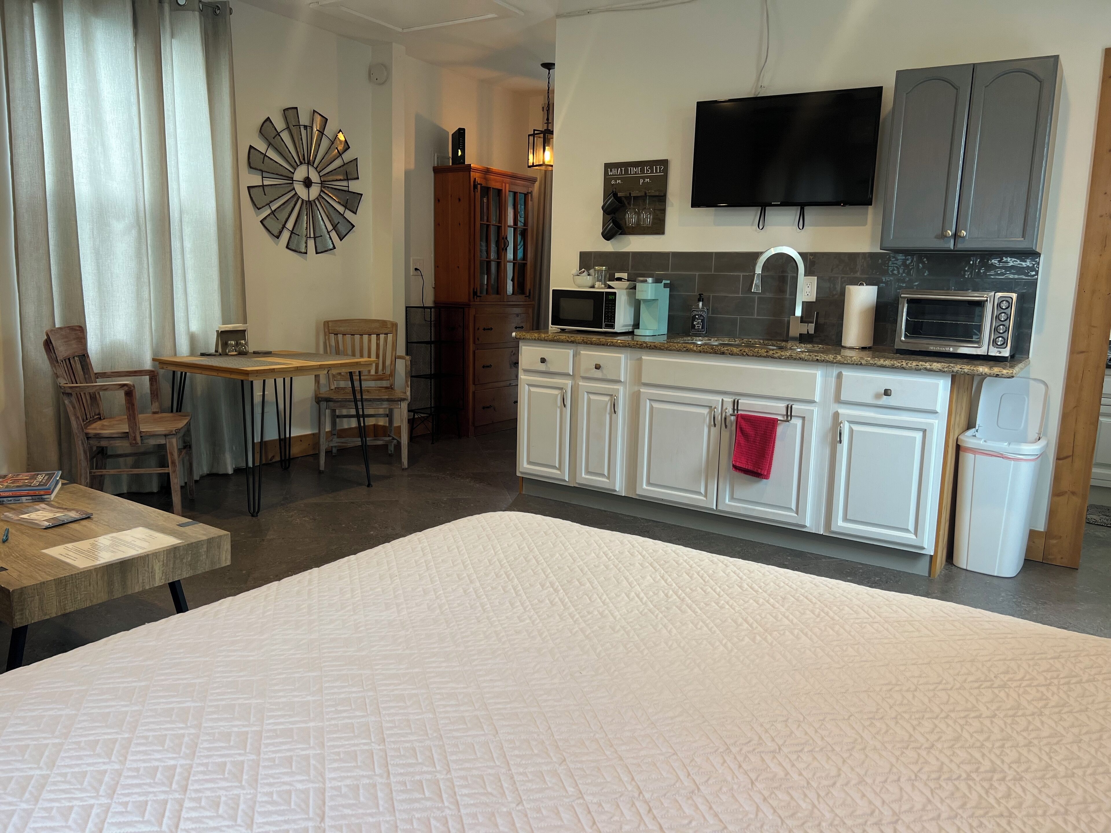 A compact kitchen with white cabinets, a microwave, a toaster, and a sink.