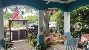Un patio cubierto con un banco de madera, una hamaca y un pequeño pabellón.