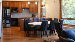 Una cocina moderna con armarios de madera, un refrigerador de acero inoxidable, un microondas y una isla grande con sillas.