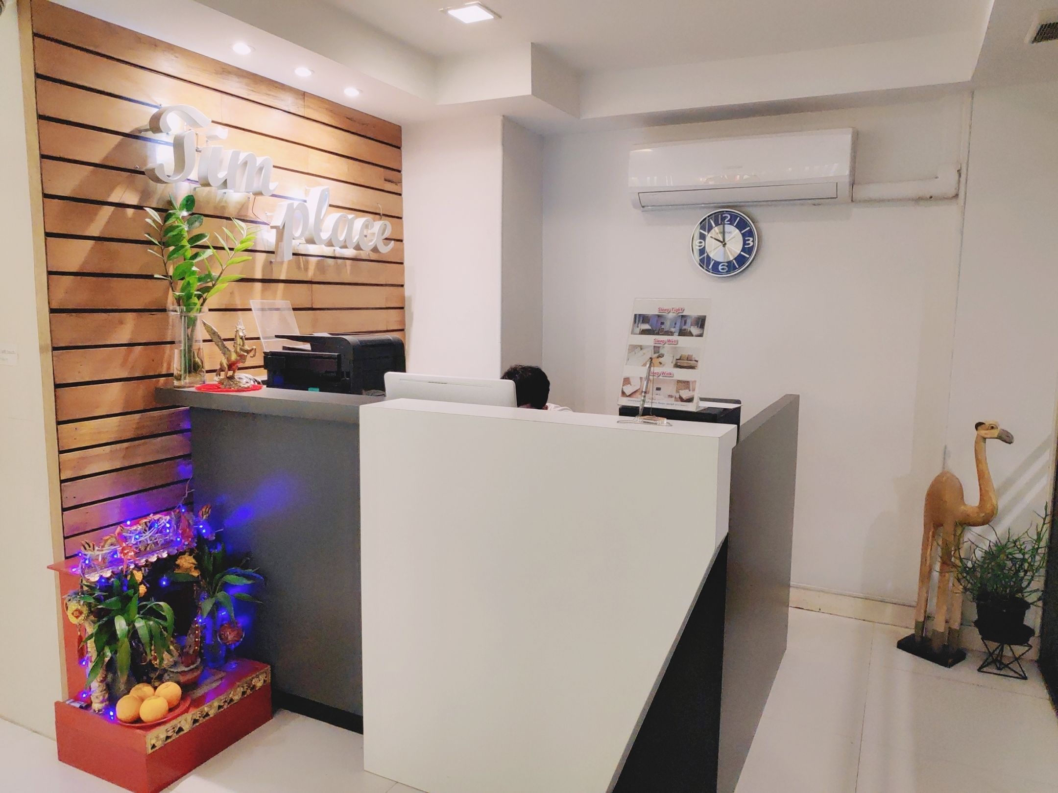 A reception area with a wooden panel wall, a reception desk, a clock, and a decorative flamingo statue.