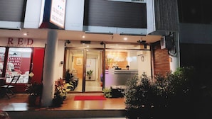 A hotel entrance with a 'Jim Place' sign, a 'RED' sign indicating a spa, and a reception area with a plant.