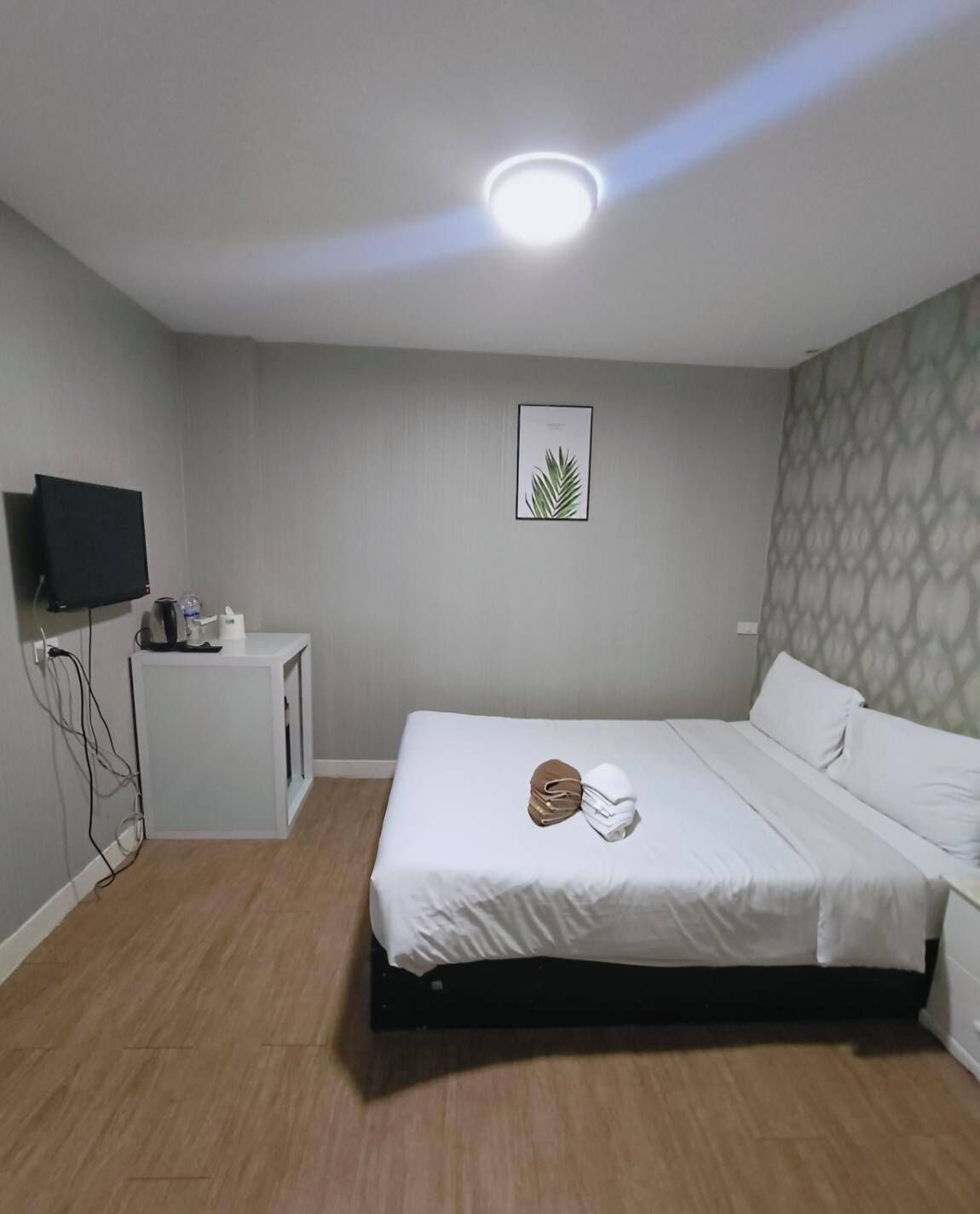 A hotel room with a bed, a small desk, a television, and a wall-mounted picture.