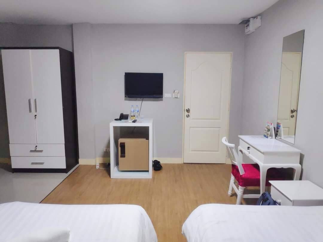 A hotel room with two beds, a TV, a desk, a wardrobe, and a door.
