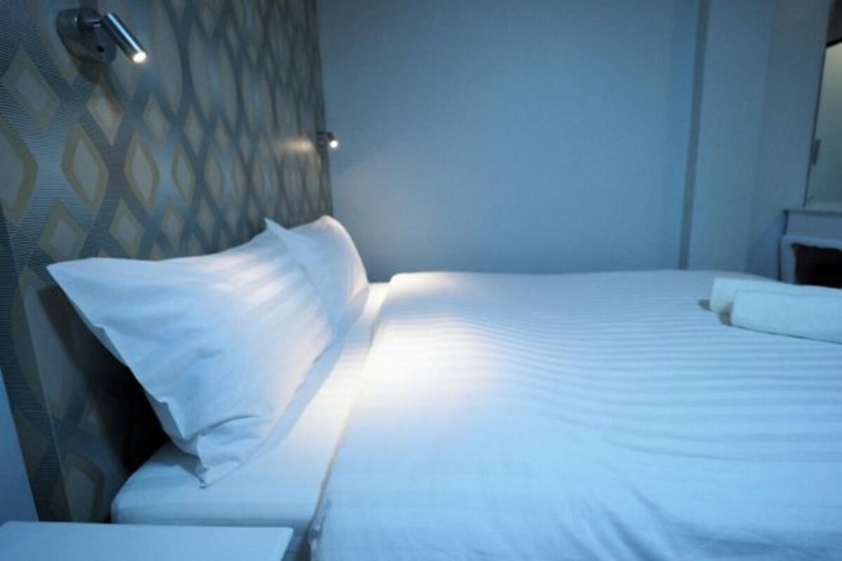 A neatly made bed with white linens in a hotel room.