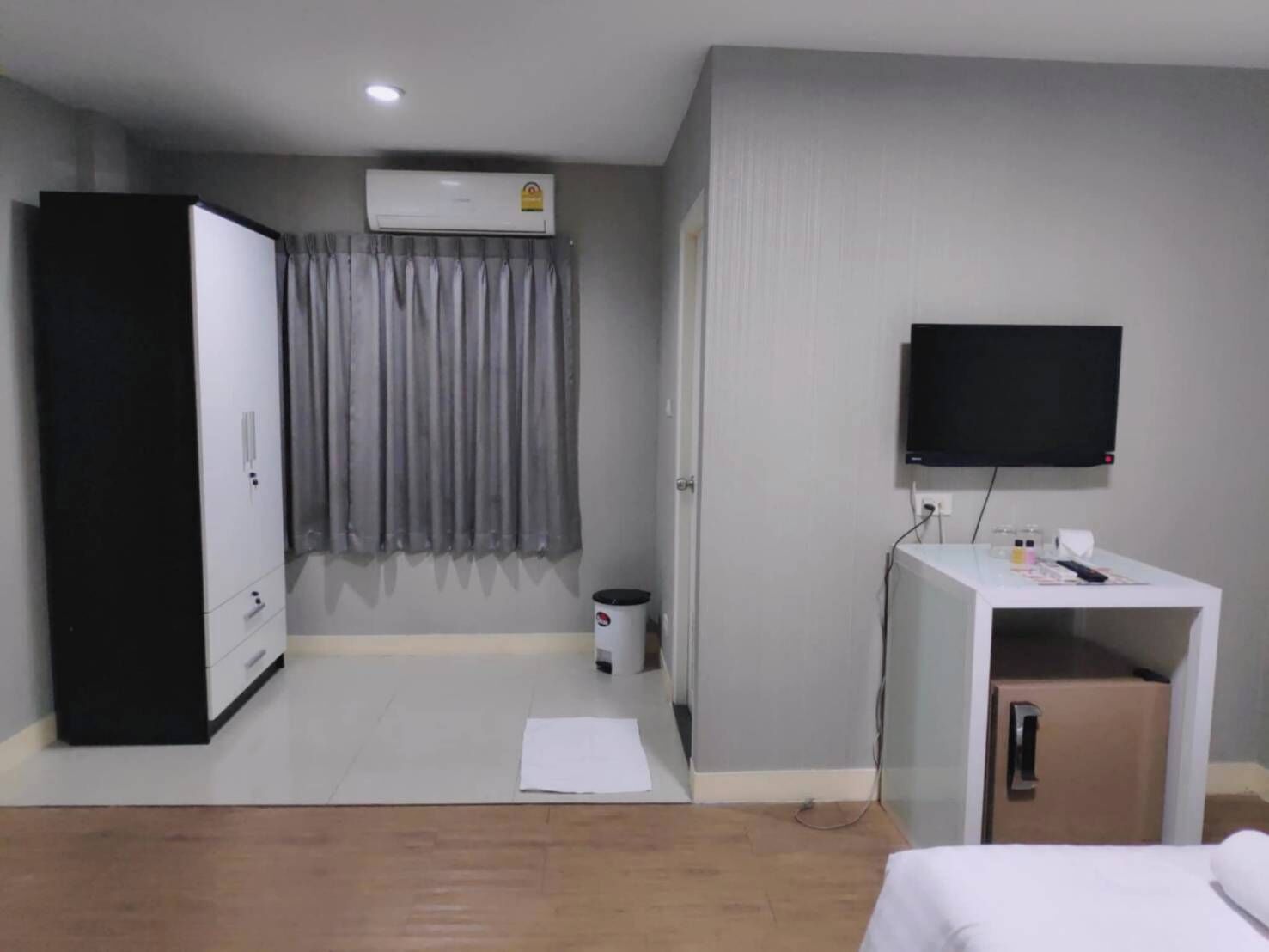 Ein Hotelzimmer mit Schrank, Fernseher, Schreibtisch mit Computer und Bett.
