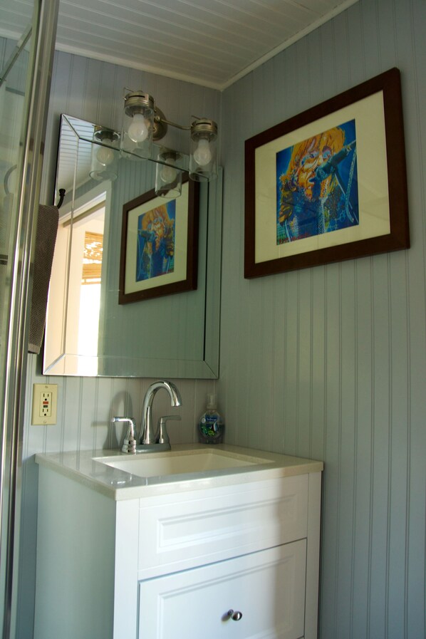 Une salle de bain avec un lavabo, un miroir et une œuvre d’art encadrée au mur.