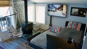 A cozy room with a bed, a hanging chair, a fireplace, and a television on the wall. - The Beach Haus on Copper Mountain Preview listing (Frisco)