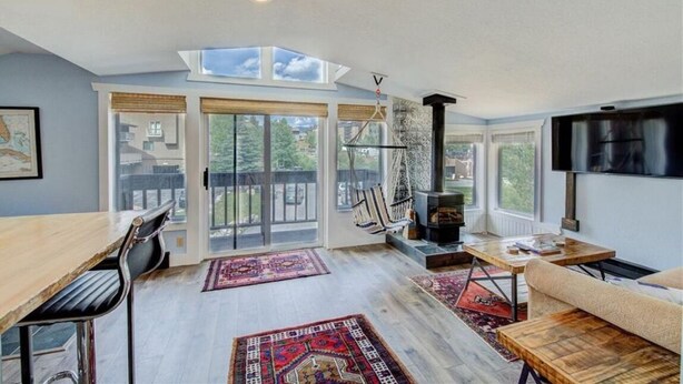 A spacious living area with a large window, a fireplace, and a TV mounted on the wall. - The Beach Haus on Copper Mountain Preview listing (Frisco)