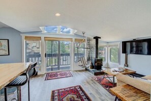Relax in a spacious living area with a high ceiling and skylight, featuring a fireplace and comfortable seating area.