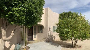 A house with a curved driveway, a wooden door, and a small window. - Tranquil Desert Retreat . Short walk to hot springs & close to Joshua Tree! (Desert Hot Springs)
