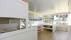 Une chambre avec des lits superposés, une petite table et une fenêtre donnant sur l’extérieur.
