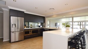 Une cuisine moderne dotée d’un grand îlot central, d’appareils électroménagers en acier inoxydable et offrant une vue sur un lac.