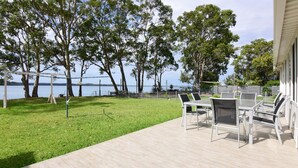 Une terrasse avec mobilier d’extérieur, une pergola et une vue sur un lac.