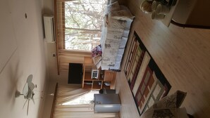 A compact living space with a kitchenette, a ceiling fan, and a window with curtains.