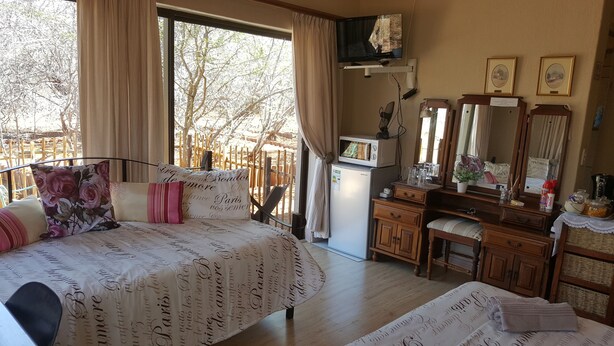 A bedroom with a bed, a dresser, a mirror, and a television.