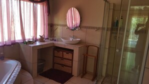 A bathroom with a sink, mirror, and shower.
