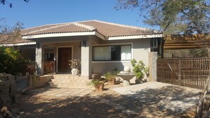 A house with a tiled roof, a front porch with steps, and a fenced yard.