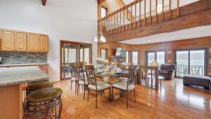 Een ruime keuken met houten kasten, een betegelde achterwand en een eethoek met een grote tafel en stoelen.