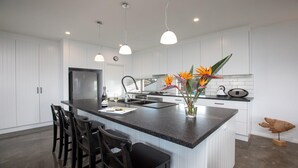 A modern kitchen with a central island, white cabinetry, and pendant lighting.