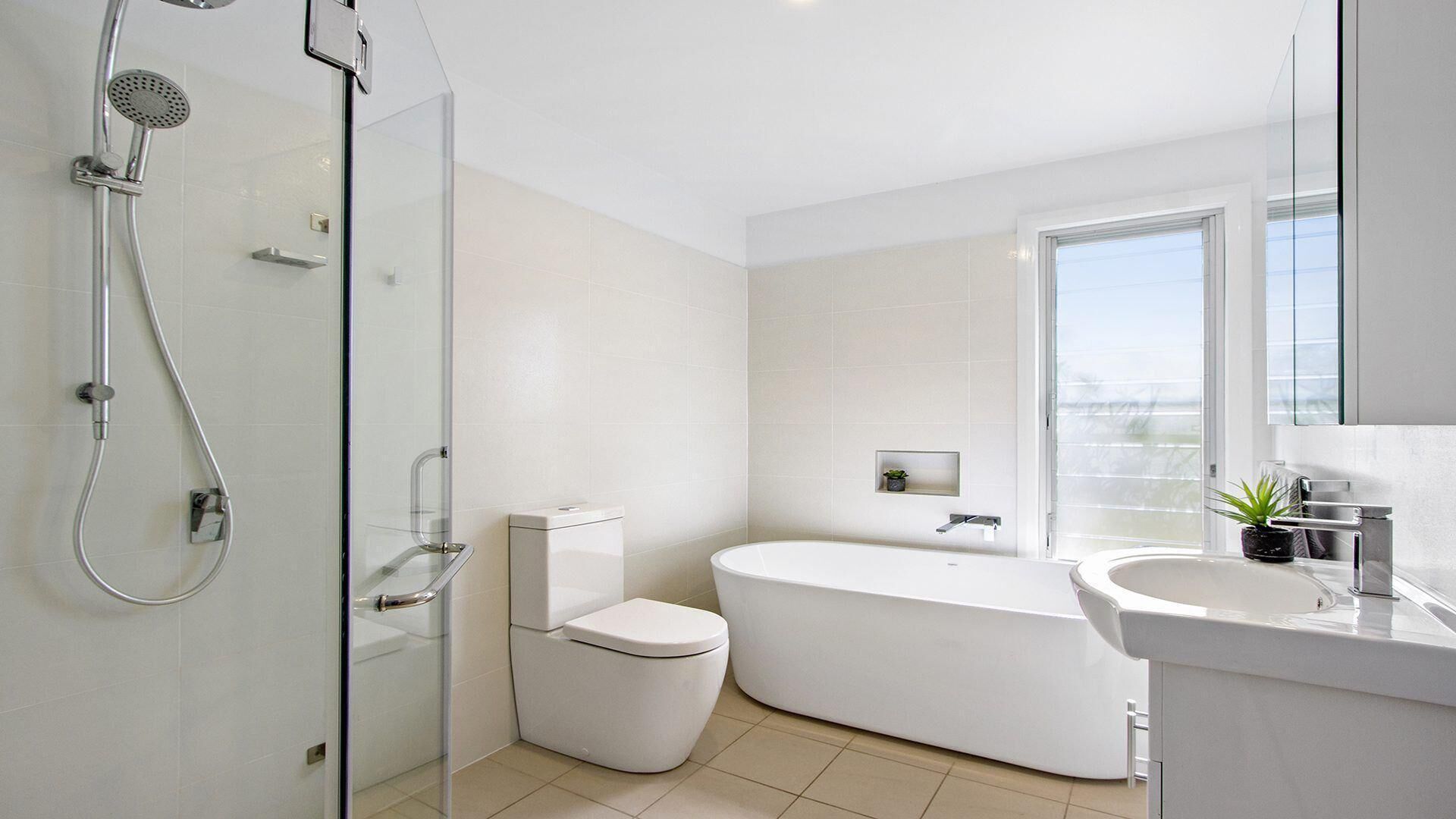 A modern bathroom with a glass-enclosed shower, a toilet, a bathtub, and a sink with a mirror.