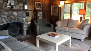 Una sala de estar acogedora con chimenea de piedra, asientos confortables y vistas al exterior.