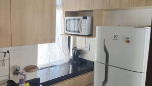 Una cocina con armarios de madera, un refrigerador blanco, un microondas, una cafetera y un lavaplatos.
