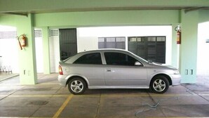 Un coche plateado estacionado en un garaje con suelos de hormigón y paredes verdes.