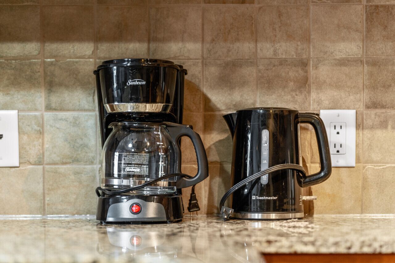 A kitchen with a coffee maker, a kettle, and a toaster on the counter.
