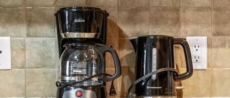 A kitchen with a coffee maker, a kettle, and a toaster on the counter.