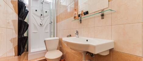 A bathroom with a toilet, sink, and shower.