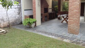 Eine Außenpatio-Terrasse mit Kamin aus Ziegelsteinen, einer Sitzbank und einem Blumentopf.