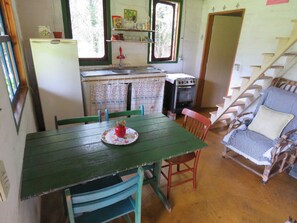 A compact kitchen with a dining area, a stove, and a chair with a cushion.