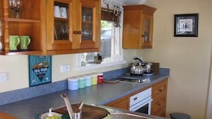 A kitchen with wooden cabinets, a stainless steel sink, and a kettle on the counter.