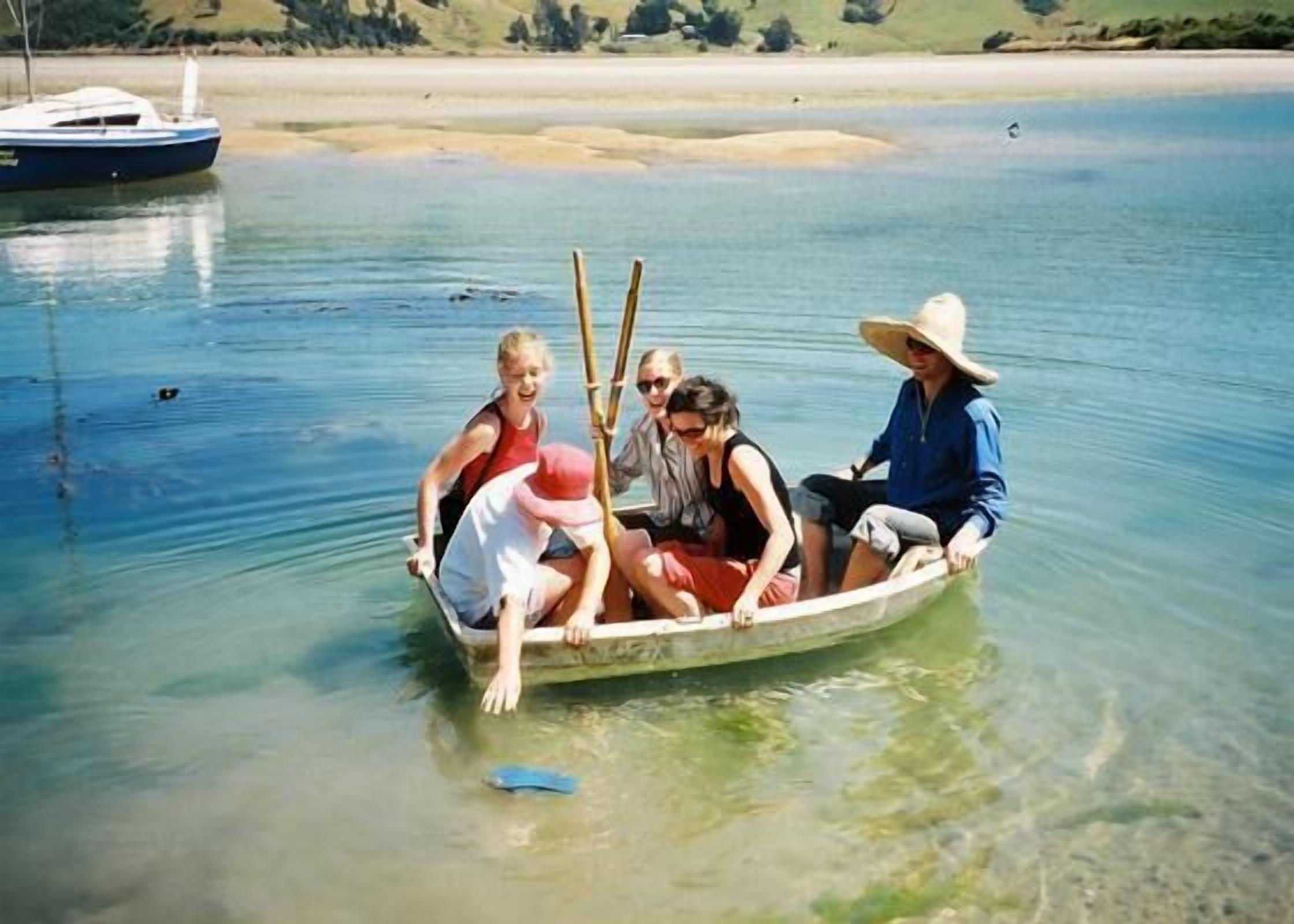 A group of people in a small boat on a calm body of water.