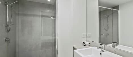 Uma casa de banho moderna com chuveiro envidraçado, uma sanita branca e um espelho grande.