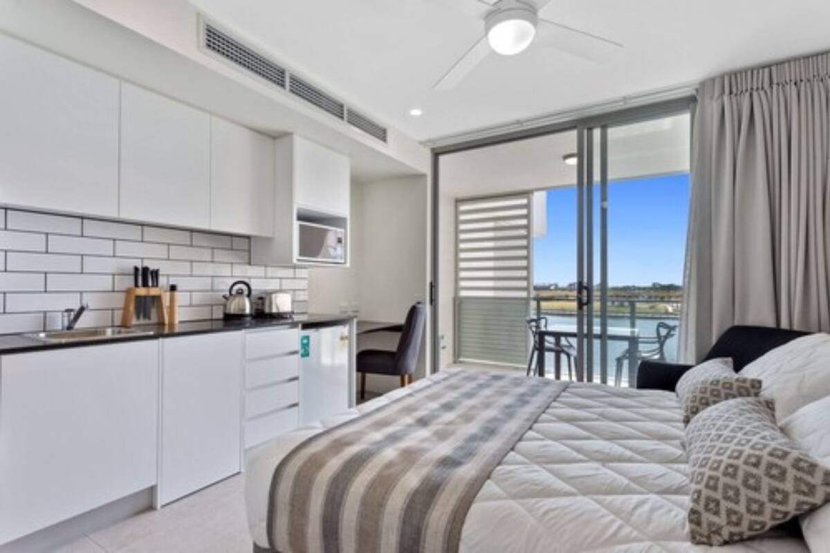 Een moderne hotelkamer met een kitchenette, een balkon met uitzicht en een groot bed met behang.