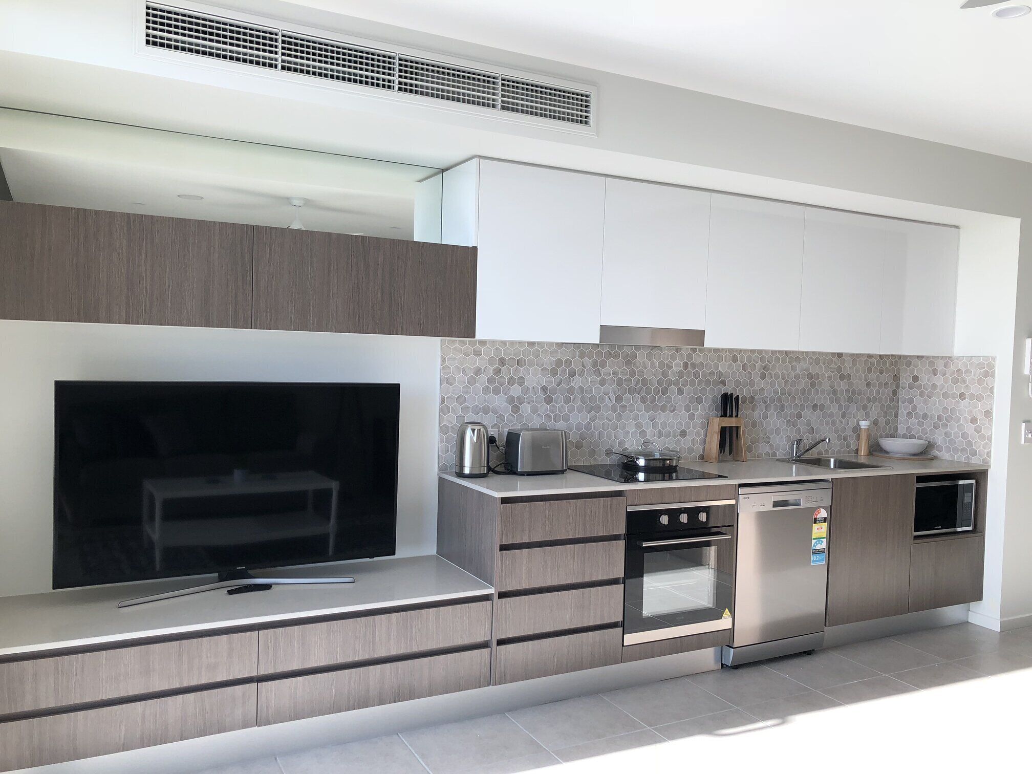 A modern kitchen with built-in appliances, a microwave, a toaster, and a kettle.