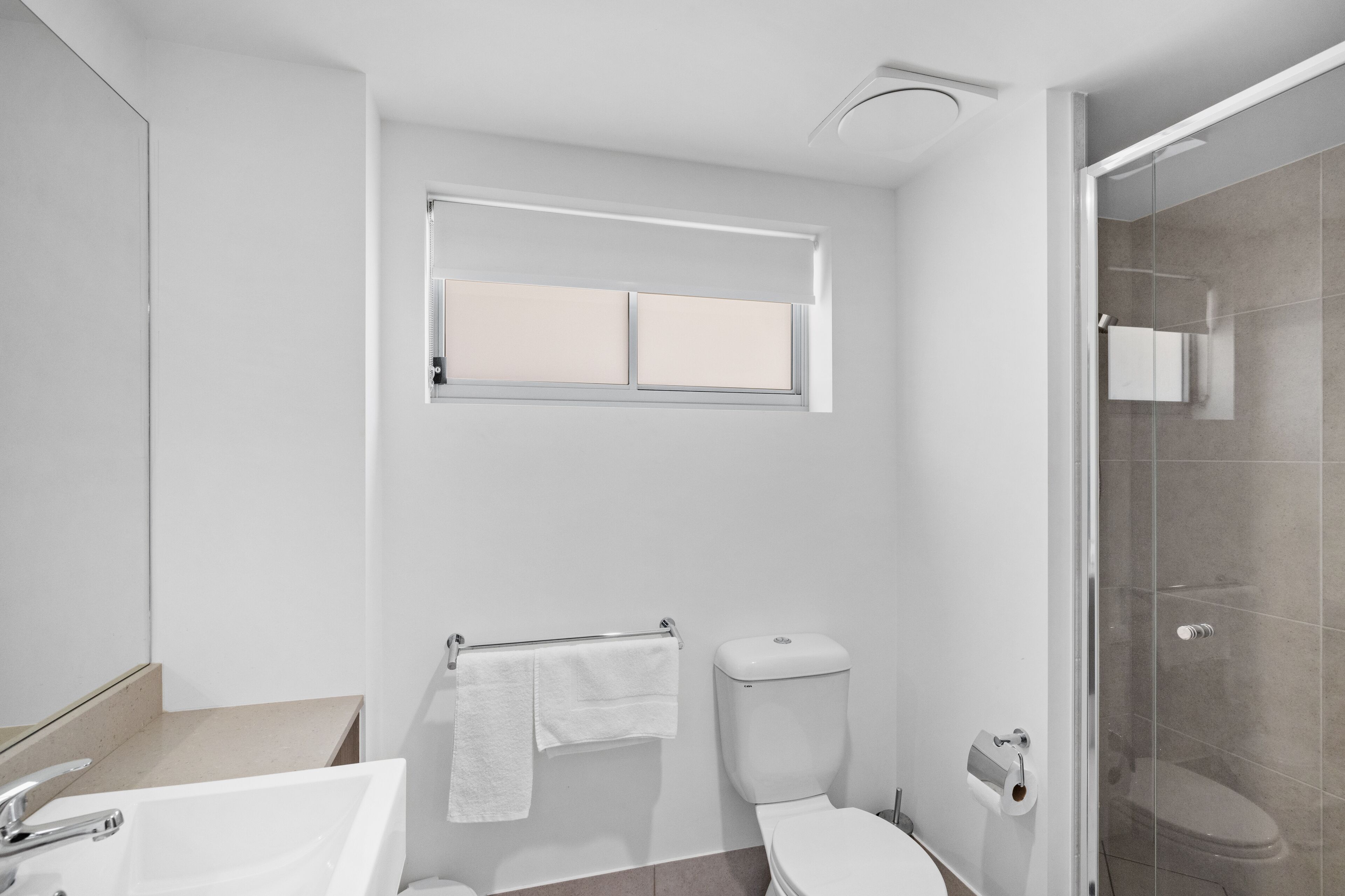 A modern bathroom with a toilet, sink, and shower.