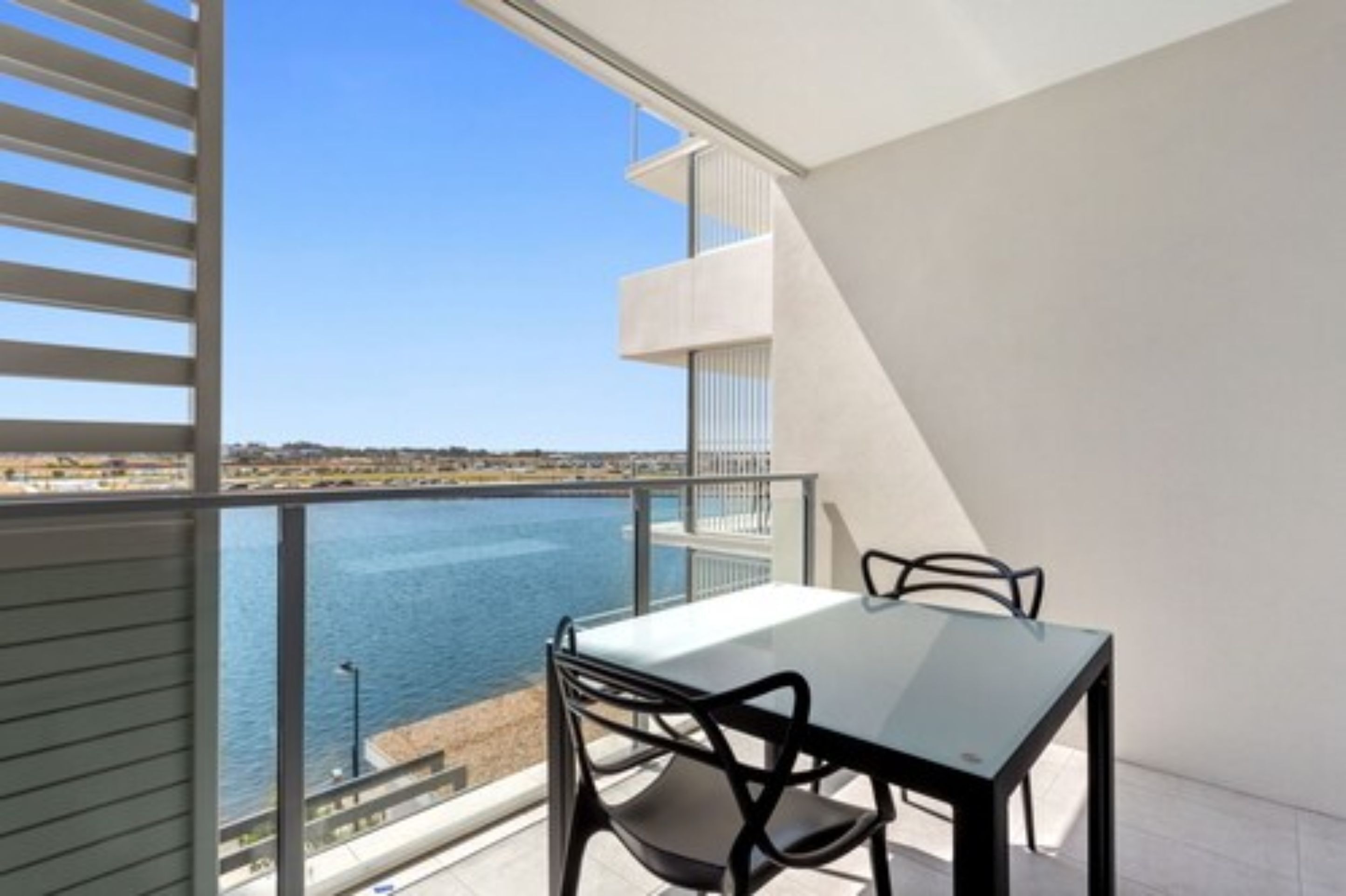 A balcony with a table and chairs overlooking a body of water.