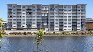 A modern multi-story building with balconies, situated next to a body of water. - North Shore Kawana and Waterline (Birtinya)