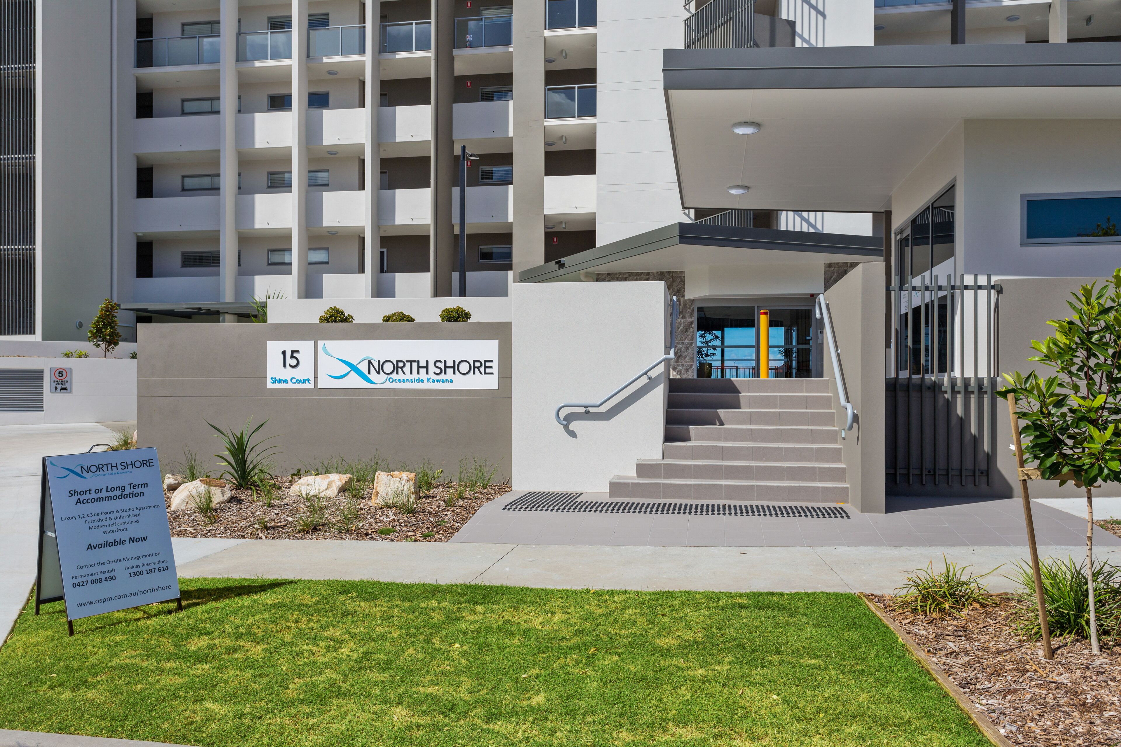 A modern building with a sign for North Shore, featuring a staircase and a well-maintained lawn.